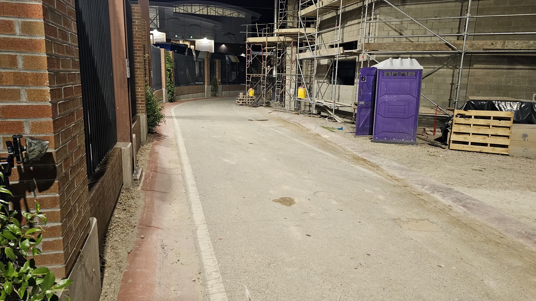 Narrow nighttime passage between Ari on Fourth construction and the neighboring Fourth Avenue entertainment property